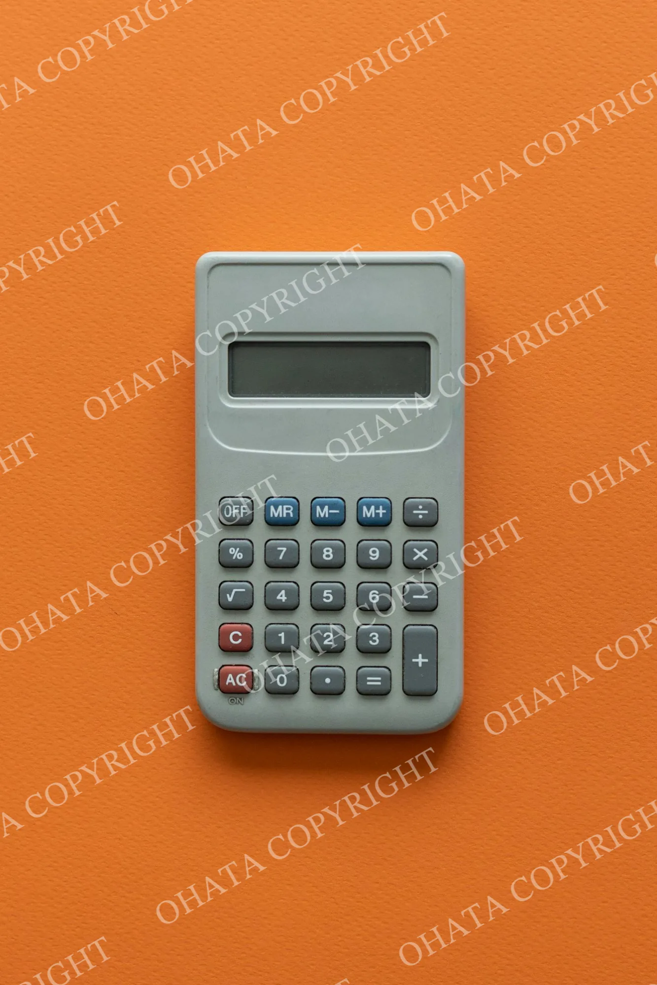 Grey calculator with a solar panel and large display on an orange background.