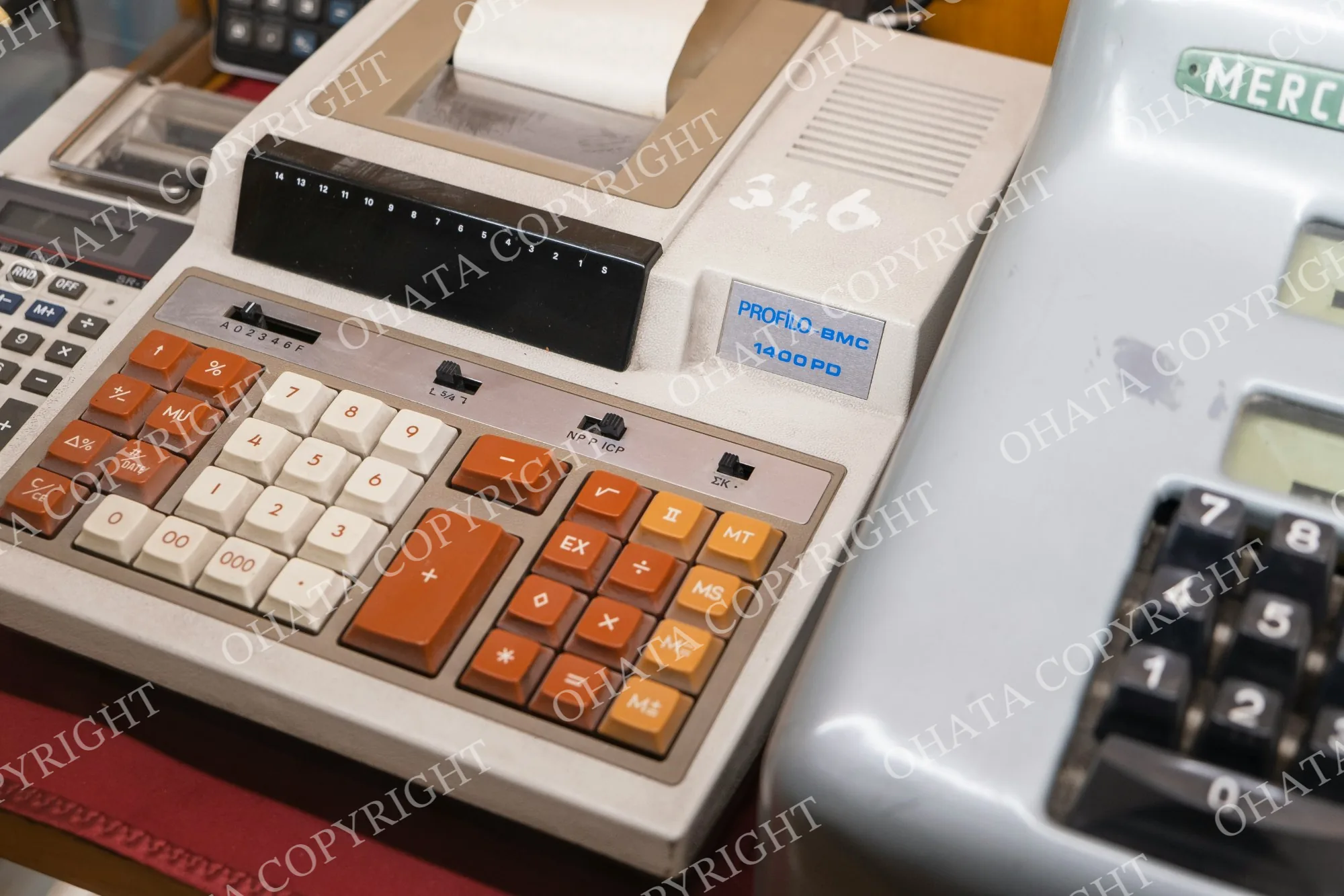 Printing desktop calculator with orange and white keys and a paper roll.