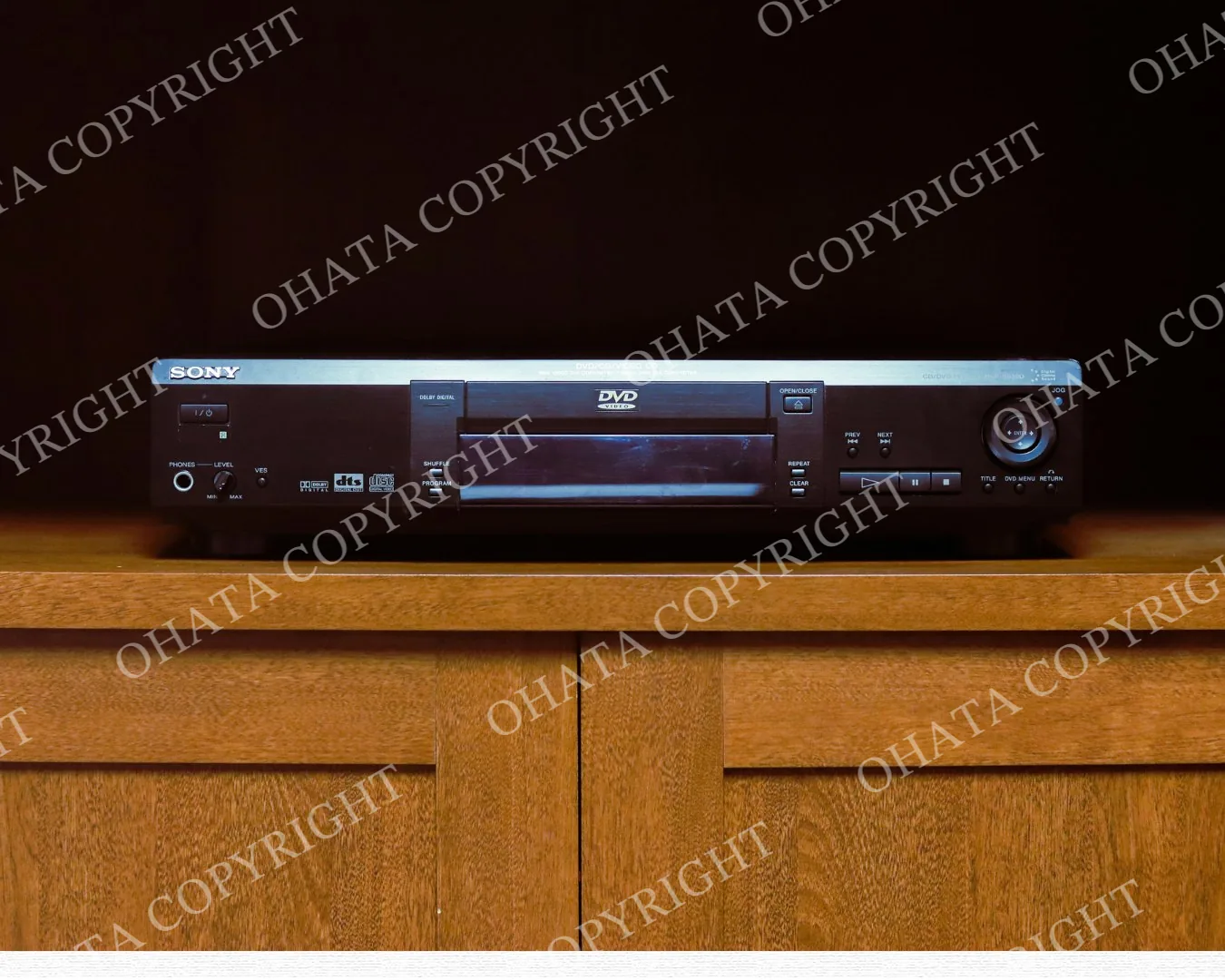 Sony standalone CD/DVD player with a front disc tray and playback controls in a wooden cabinet.