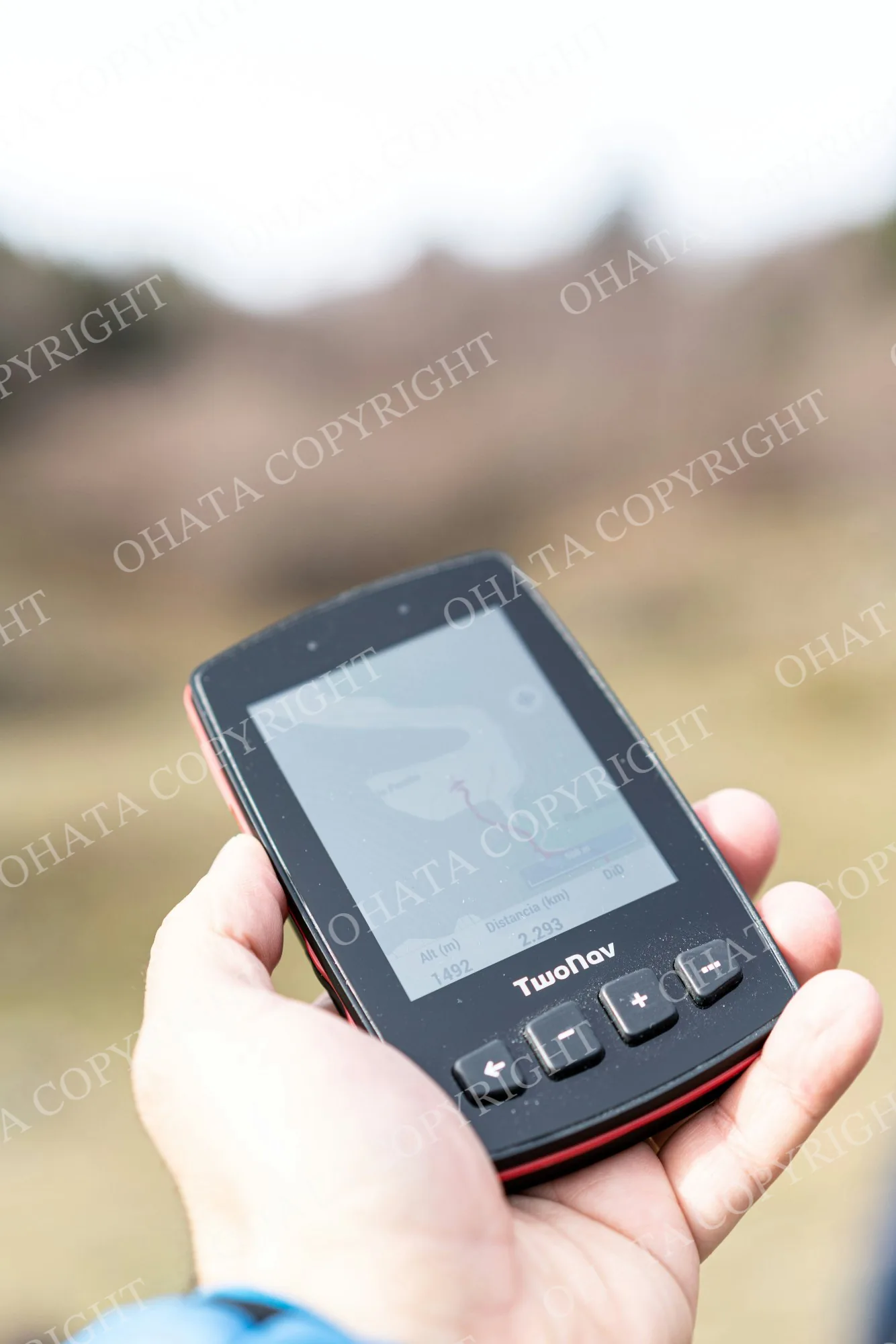 Handheld TwoNav GPS navigation device displaying a route map outdoors.