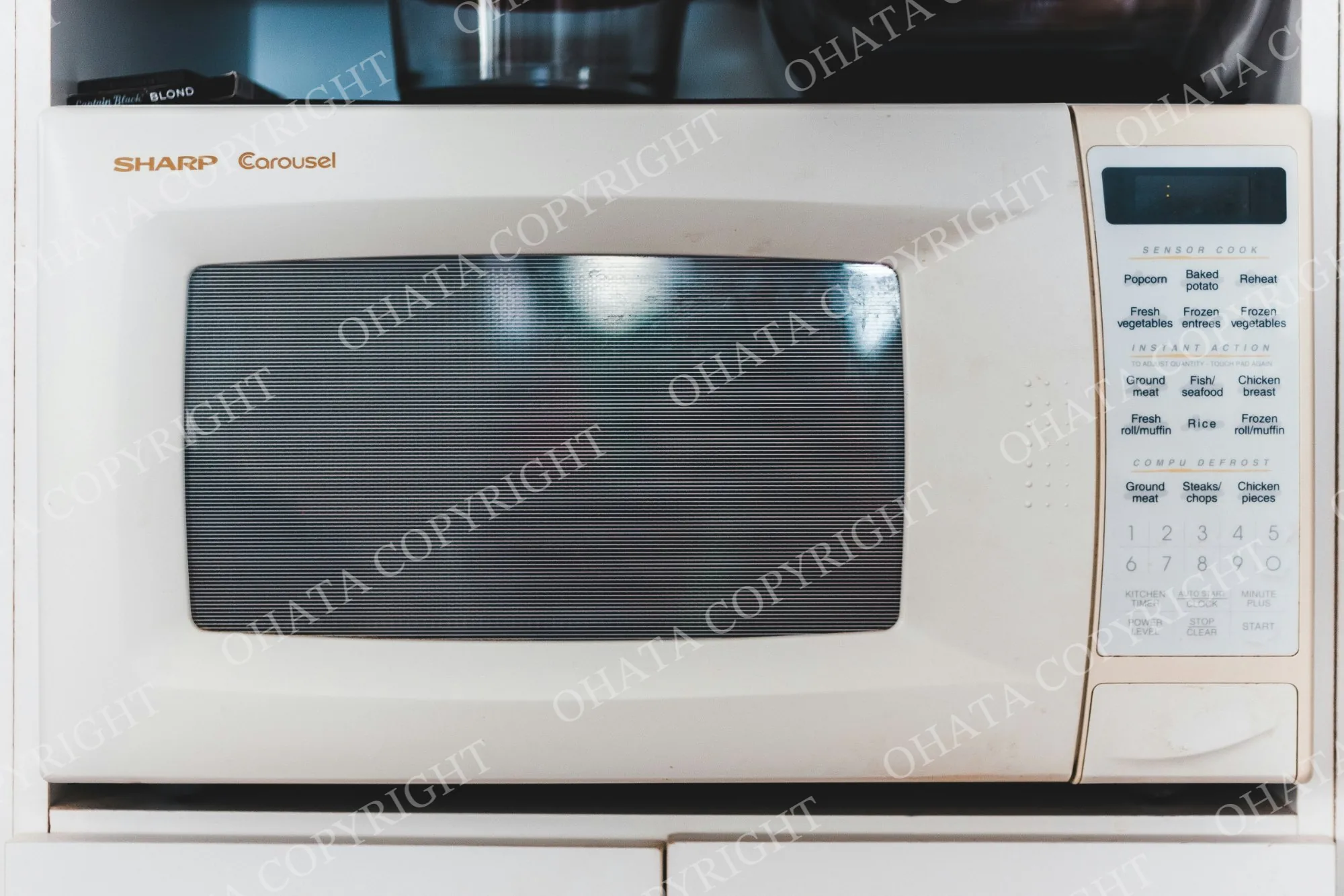 Older white Sharp Carousel microwave with a front window and keypad controls.
