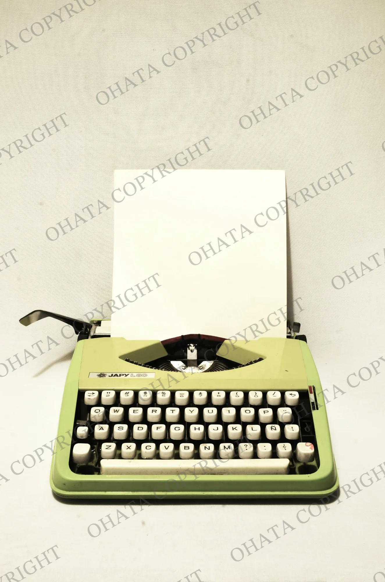 Green Japy manual typewriter with a blank sheet of paper in the paper feed.