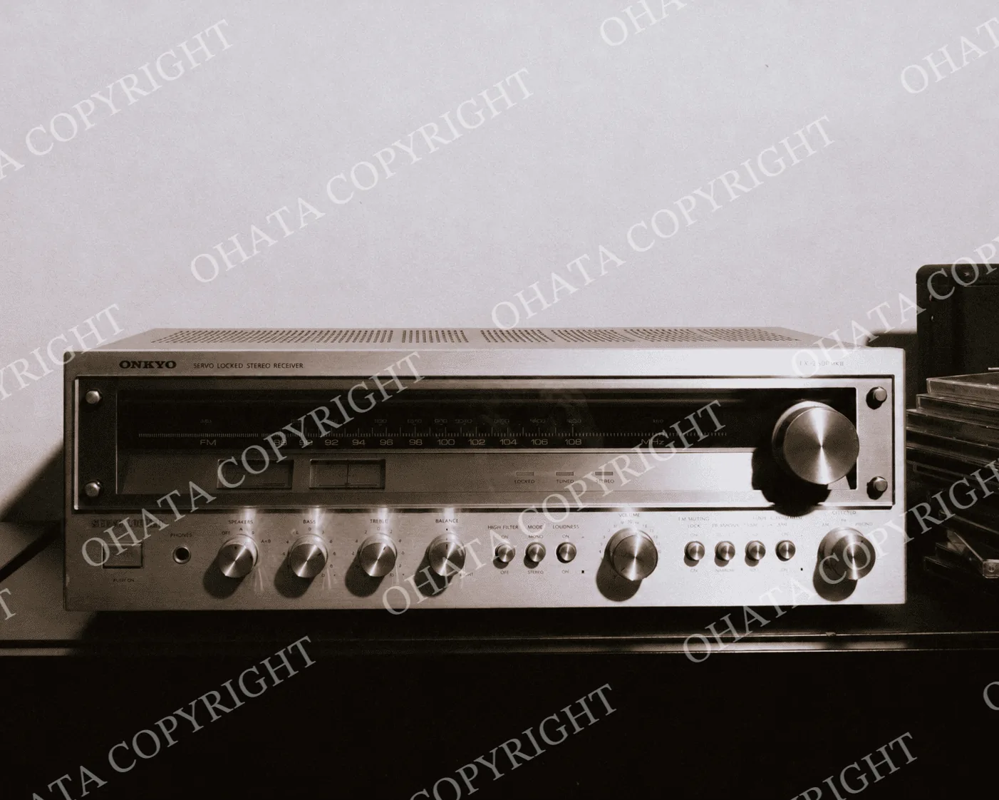 Silver Onkyo stereo receiver with a radio tuning scale and control knobs, beside a turntable and stacked CDs.