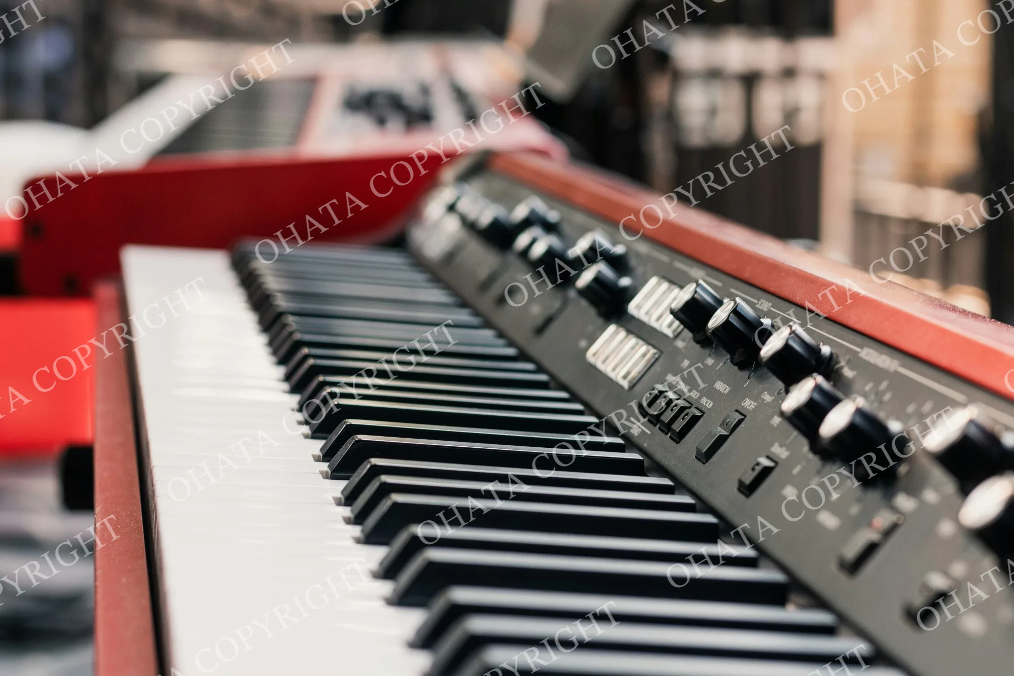 Close-up of a red electronic keyboard showing black and white keys, control knobs and switches.