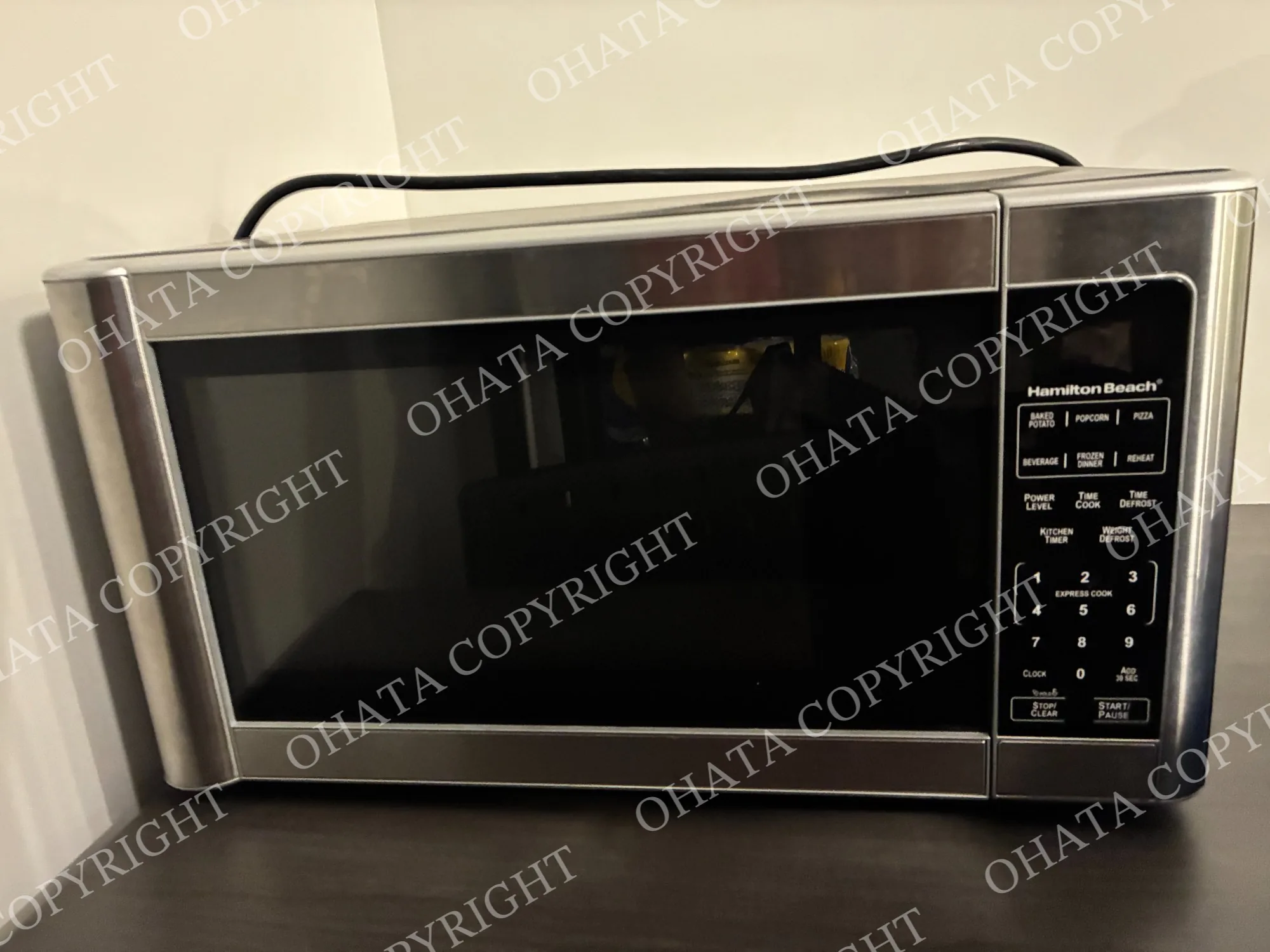 Hamilton Beach countertop microwave with a stainless-steel finish, black door, and keypad controls.