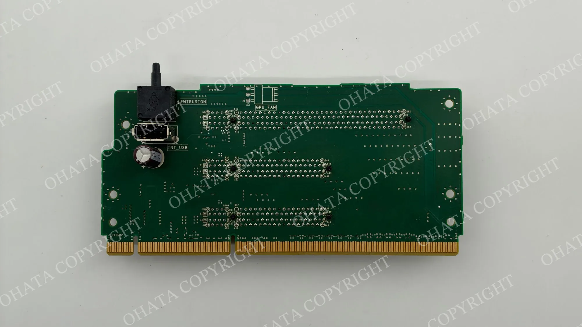 Reverse side of a green expansion board with gold-plated edge contacts and rows of through-hole connector pins.