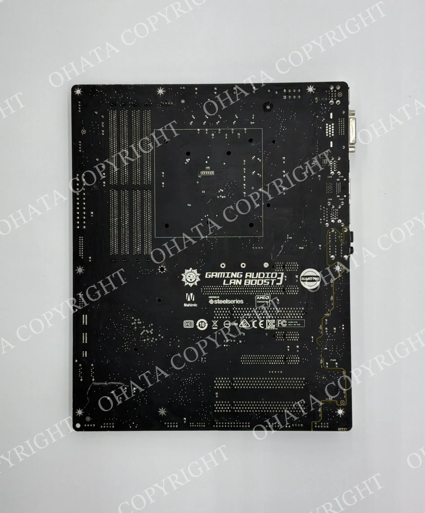 Rear side of an MSI B150 Gaming M3 motherboard showing solder joints, printed branding, certification symbols, and PCB markings.