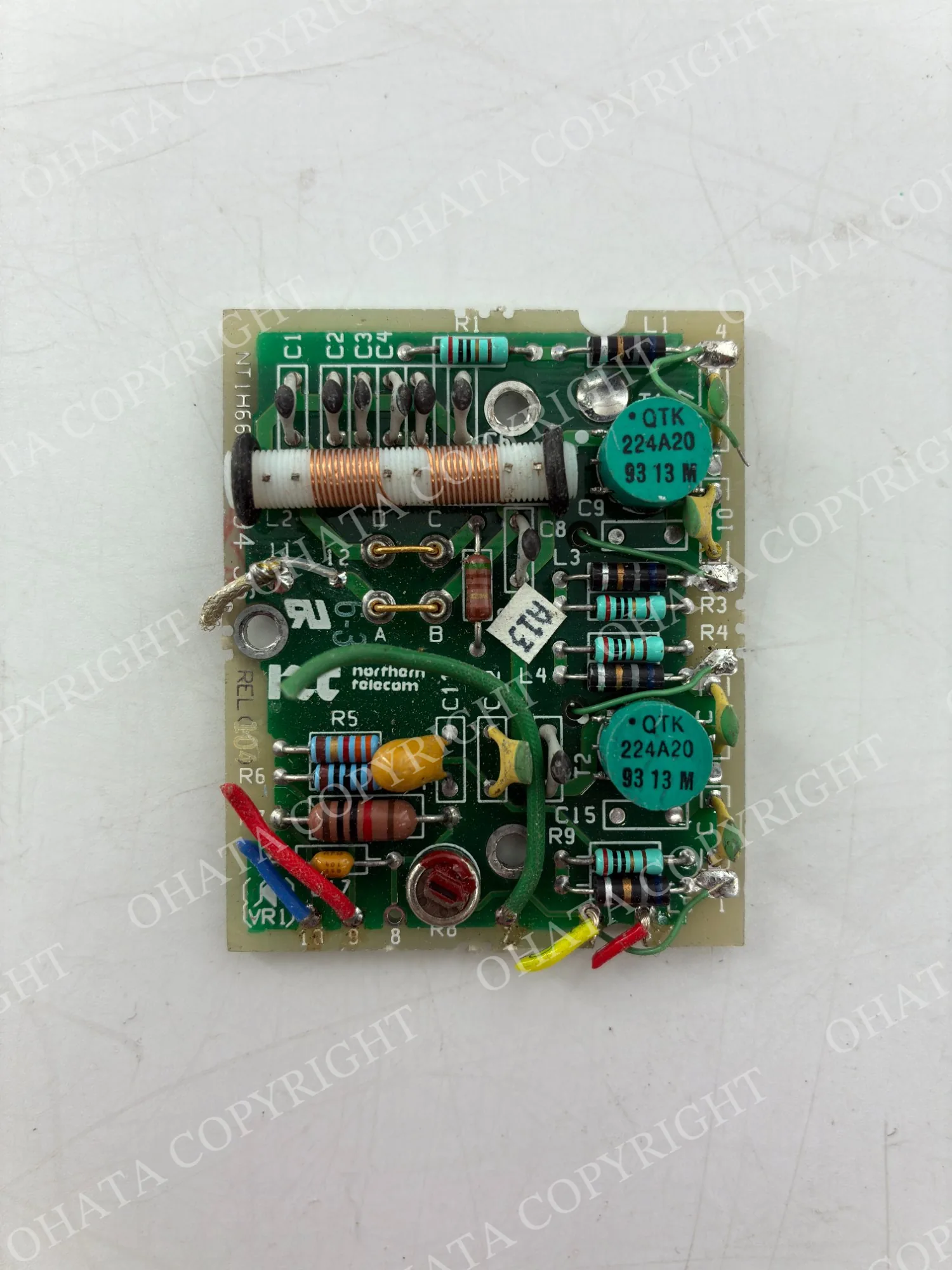 Front view of a Northern Telecom circuit board with coils, resistors, capacitors, attached wires, and other through-hole components visible.