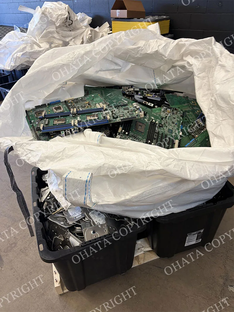 Server motherboards in a bulk bag above containers of complete hard drives near Vancouver