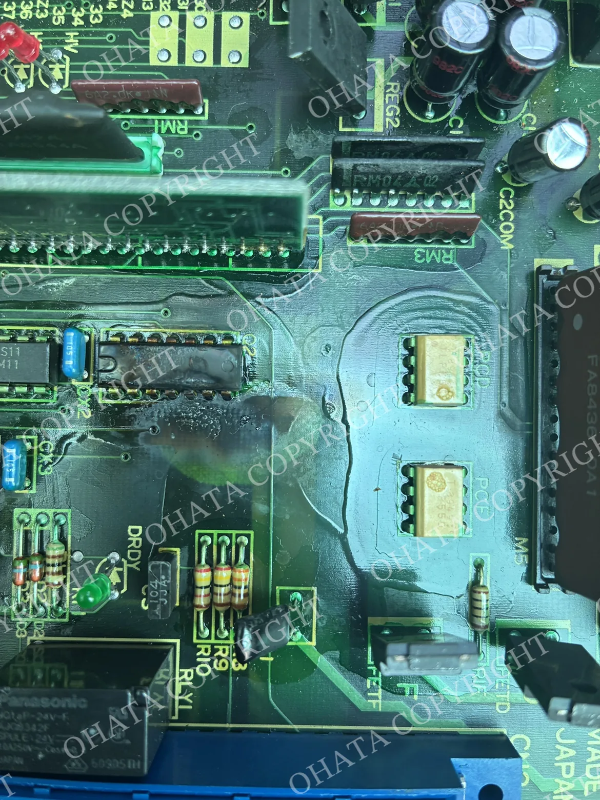 Close-up of a burned integrated circuit with dark discoloration and visible heat damage on the surrounding PCB.
