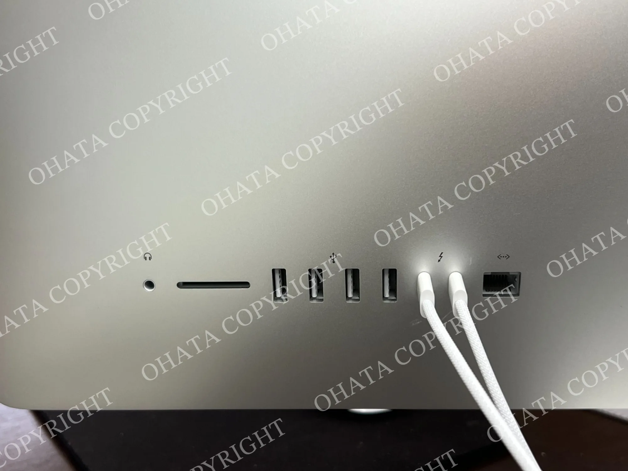 Close-up of the rear ports on an Apple iMac showing a headphone jack, card reader, USB ports, Thunderbolt connections, and Ethernet port.
